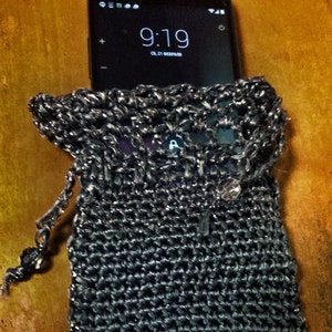 Grey crochet clutch bag holding a smartphone, showing the phone fits snugly inside the beaded evening purse.
