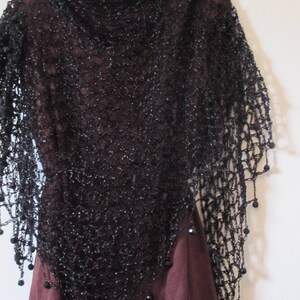 Black lurex shawl draped over a burgundy dress, front view of the sparkling wrap and beaded trim.