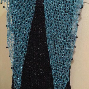 Turquoise shawl hanging straight over a black dress, symmetric front view of the sparkling wrap.