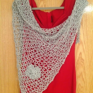 Silver floral shawl draped over a red dress on a hanger, front view with a flower applique visible.