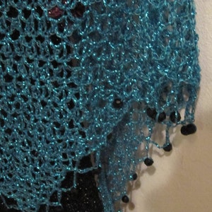 Close-up of the turquoise lurex crochet, revealing tight hand stitches and dark beads along the scalloped edge.