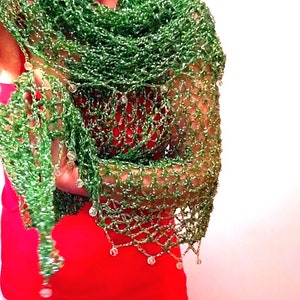 Woman in a red dress wearing a green lurex crochet shawl, the beaded edge with hanging beads draped over her arm.