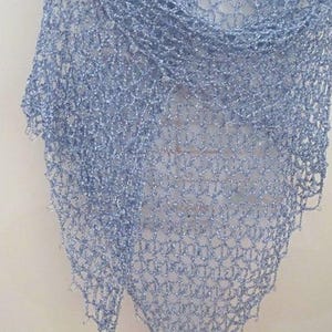 Sky blue lurex crochet shawl hanging in a full view, delicate openwork catching the light.