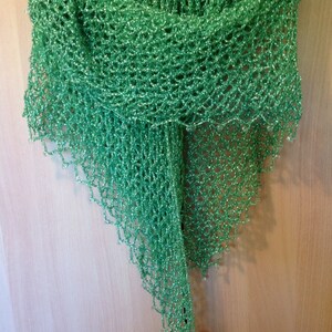 Bright green lurex shawl hanging on a wooden door, draped to a long point.
