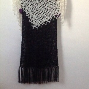 Cream shawl layered over a black fringed dress, front view of the ivory openwork.