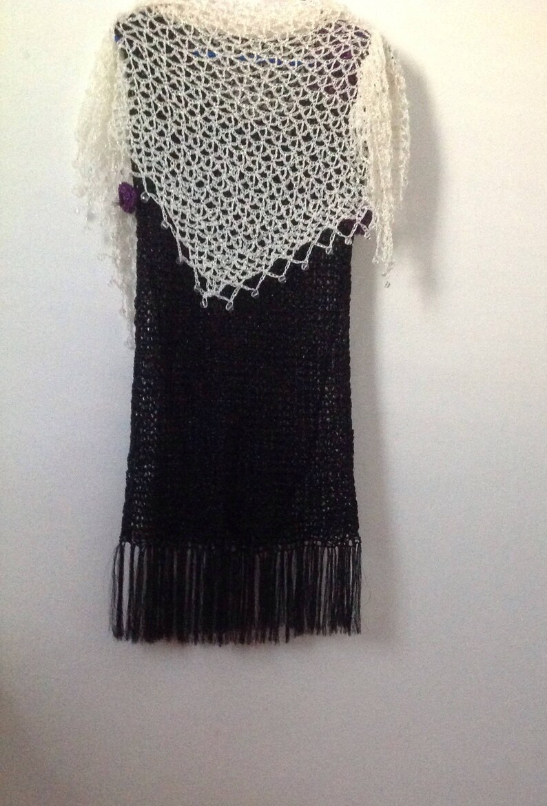 Cream shawl layered over a black fringed dress, front view of the ivory openwork.