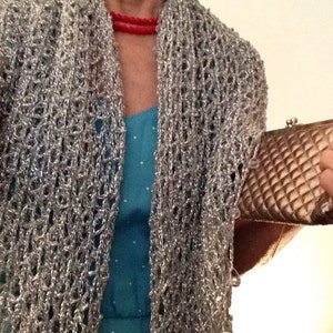 Woman in a turquoise dress with the silver shawl, holding a metallic clutch at her side.