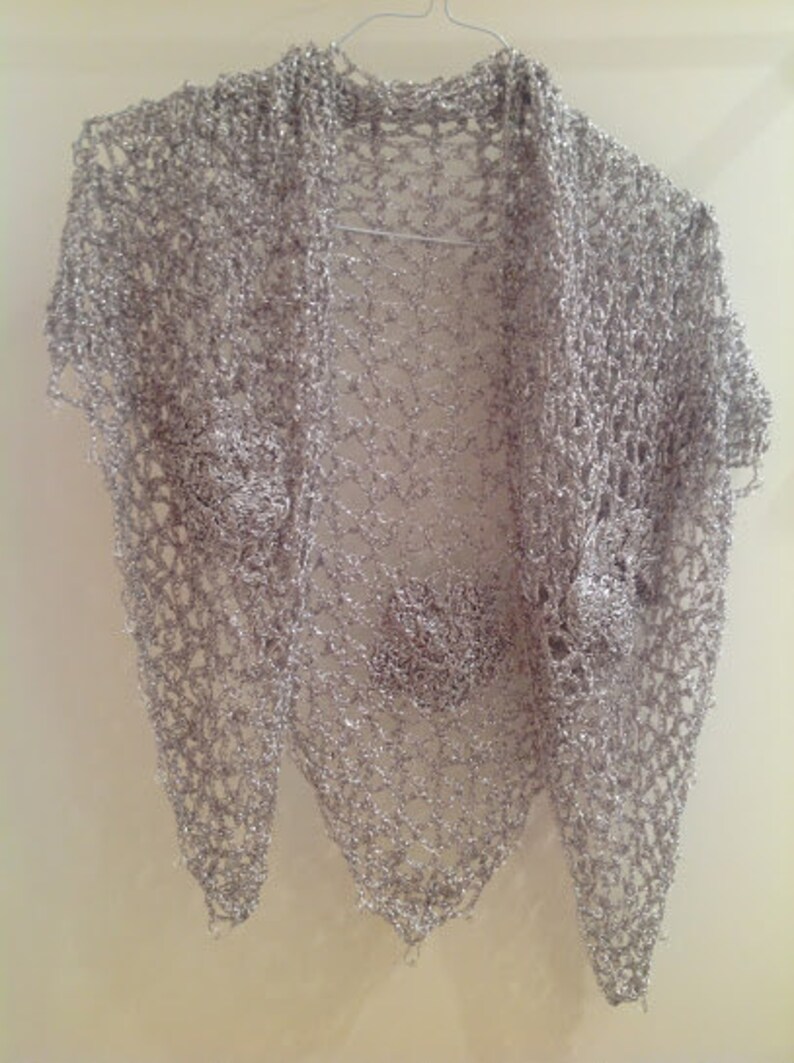Silver floral shawl hanging flat on a hanger, full view of the openwork and scattered flower motifs.