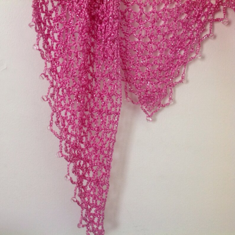 Close-up of the pink openwork crochet, showing the fine stitches and beaded edge.