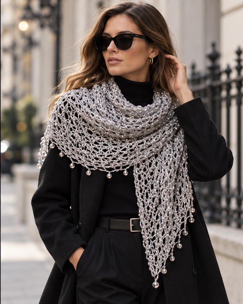 Woman in a black outfit wearing the silver beaded shawl, iron fence and city street in the background.