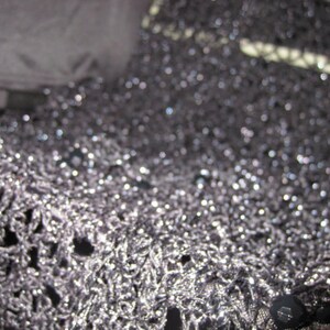 Close-up of the black lurex crochet texture, glittering stitches catching the light.