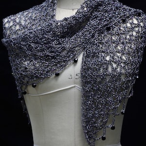 Grey beaded crochet shawl draped on a dress-form mannequin, front view with dark beads along the edge.