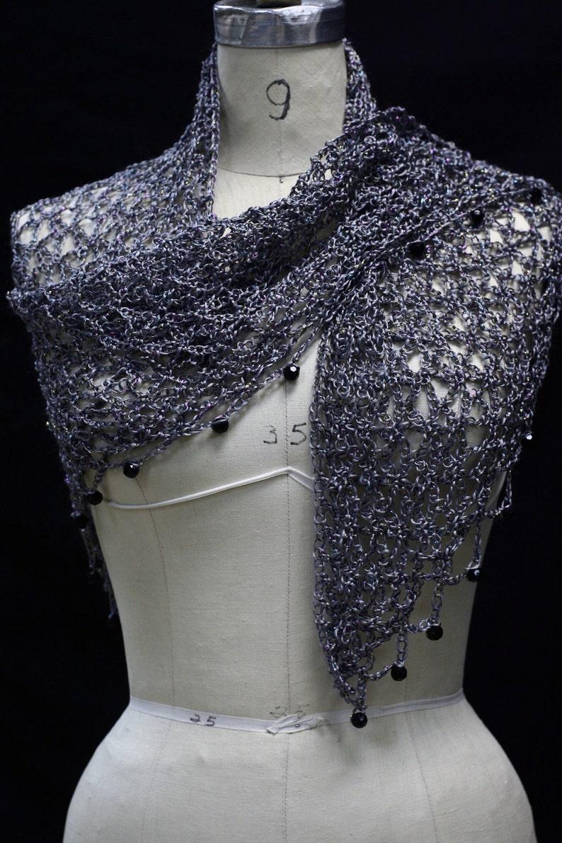 Grey beaded crochet shawl draped on a dress-form mannequin, front view with dark beads along the edge.