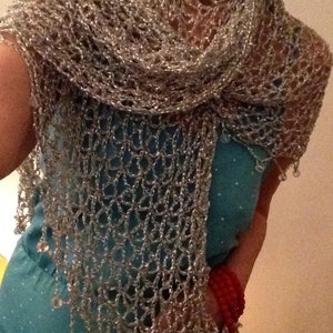 Woman in a turquoise dress wearing the silver crochet shawl around her shoulders, red bracelets at her wrist.