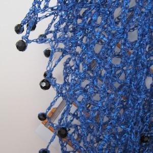 Close-up of the sapphire shawl's edge, dark beads hanging from the bright blue crochet.