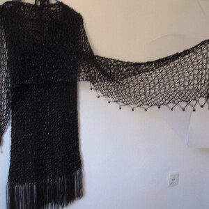 Black shawl spread wide over a black dress, full view of the airy openwork pattern.