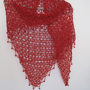 Red shawl hanging flat, full triangle view of the openwork pattern with beaded points along the hem.