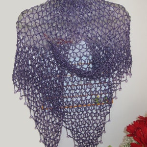 Purple shawl on a hanger, front view of the openwork with red flowers at the corner.