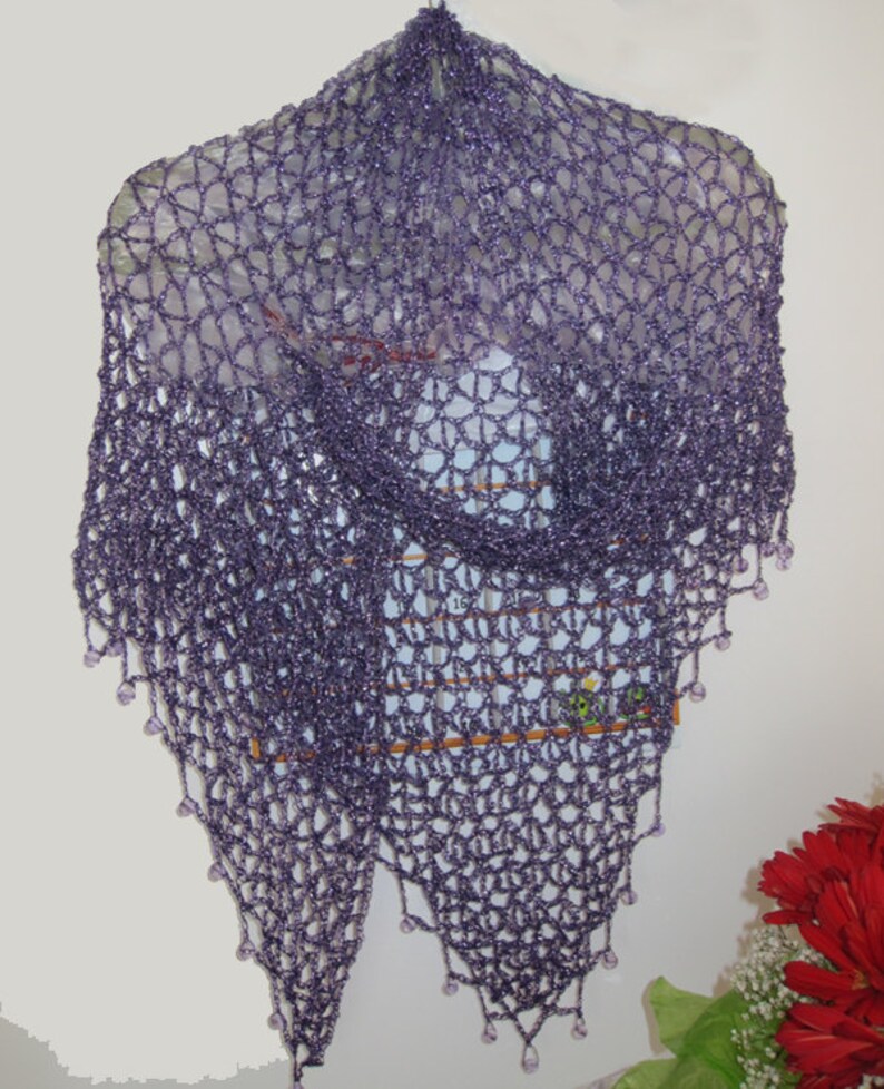 Purple shawl on a hanger, front view of the openwork with red flowers at the corner.