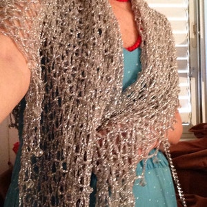 Side view of a woman in a silver lurex shawl over a turquoise dress, the wrap cascading past her waist.