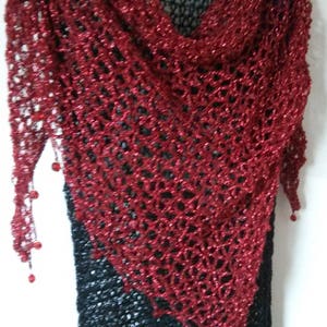 Front view of the red lurex shawl, showing the pointed hem, beaded trim, and dense sparkle of the weave.