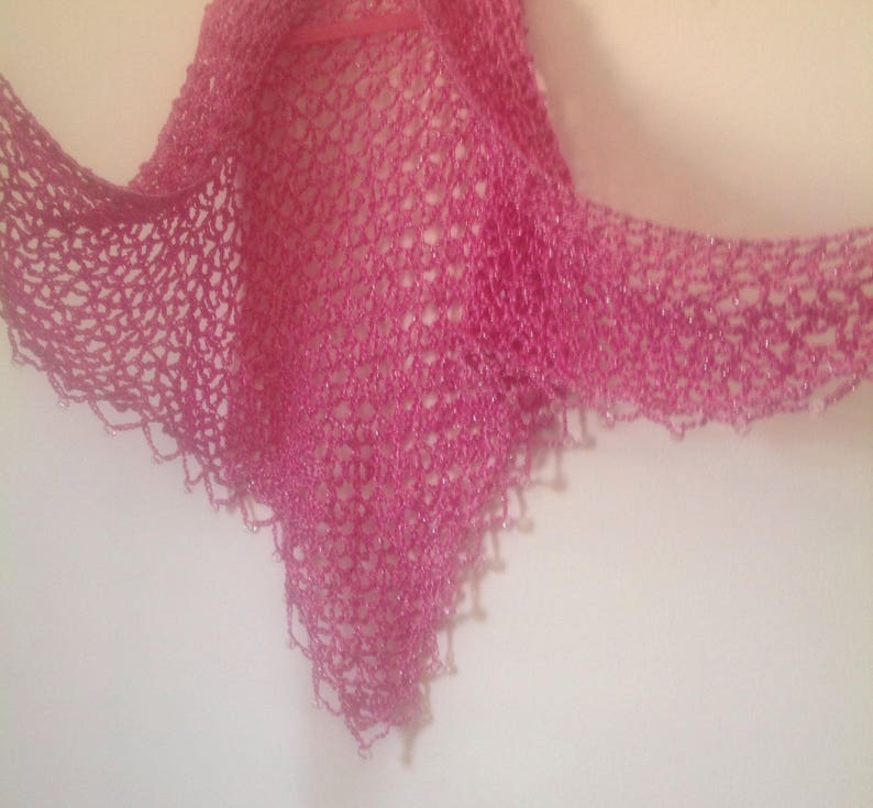 Pink shawl spread wide, showing the full width of the shimmering openwork.