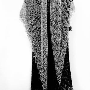 Silver beaded shawl layered over a black fringed dress on a hanger, front view of the sparkling wrap.