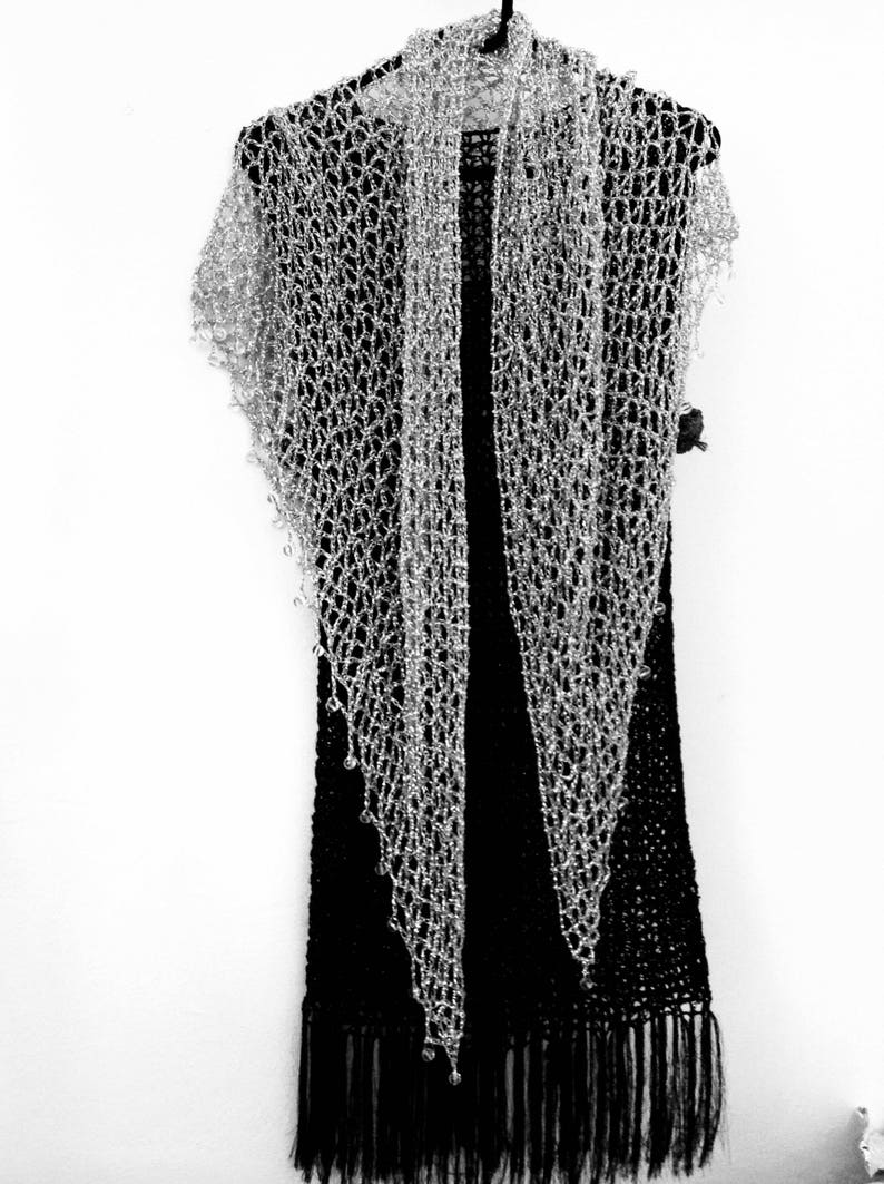 Silver beaded shawl layered over a black fringed dress on a hanger, front view of the sparkling wrap.
