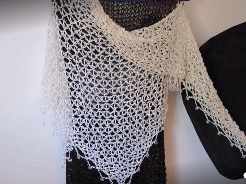 Close-up of the cream openwork crochet against the black dress, showing the fine stitch pattern.