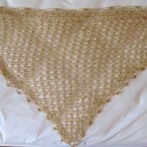 Gold beaded shawl laid flat in a triangle on a white surface, full view of the even crochet stitches and beaded edge.