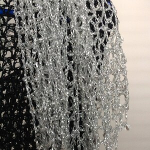 Close-up of the silver lurex crochet texture, revealing tight hand stitches, fine beads, and metallic sparkle.