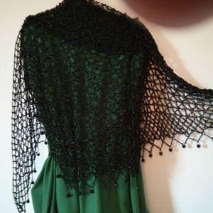 Black shawl draped over a green dress, back and side view of the openwork wrap.