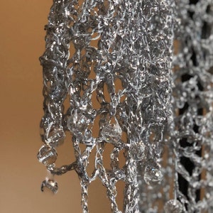 Close view of the silver shawl's beaded fringe edge, with dangling beads along the scalloped trim.