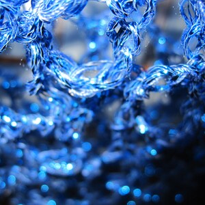 Extreme close-up of the sapphire lurex crochet, glittering blue stitches in fine detail.