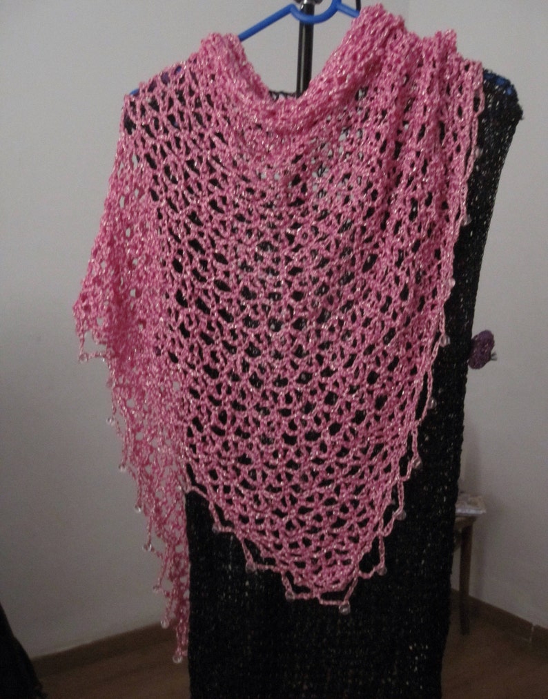 Pink lurex shawl on a hanger over a black dress, front view of the beaded openwork.