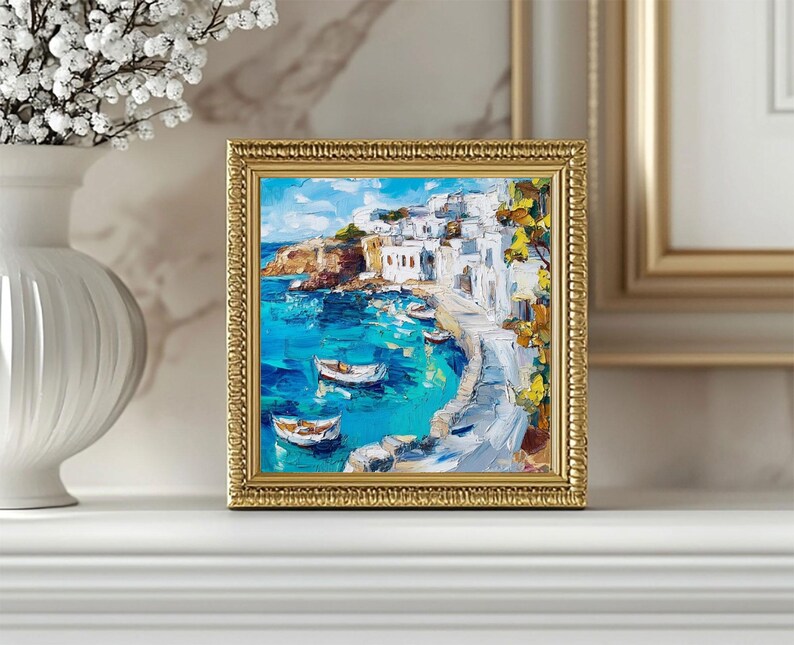 May include: A framed painting of a seascape with white buildings on a hillside overlooking a turquoise bay.  The painting is done in a loose, impressionistic style with visible brushstrokes.  There are several small boats in the water.