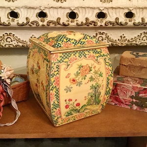 Peut inclure: Une boîte en étain vintage à motifs floraux jaunes et verts avec un couvercle à charnière. La boîte a une forme rectangulaire arrondie et est décorée d'un motif floral et d'un motif à carreaux verts et jaunes.