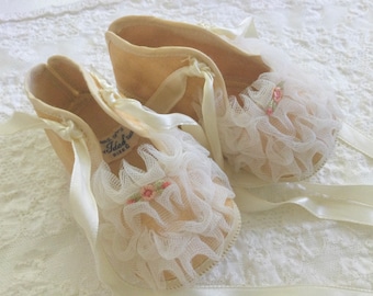 Zapatos de bebé antiguos con cinta rosa, volantes y patuquitos
