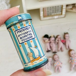 May include: A vintage blue and white tin of Mennen Antiseptic Borated Powder. The tin has a sailboat and a baby on it. The text on the tin reads "Mennen Antiseptic Borated Powder".