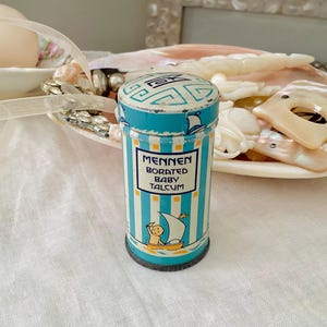 May include: Vintage blue and white striped tin with a yellow label that reads "Mennen Borated Baby Talcum". The tin features a cartoon image of a baby in a sailboat.