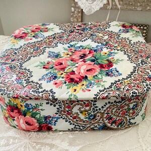 May include: A vintage floral patterned box with a paisley design. The box is white with pink, red, and yellow flowers. The box is made of cardboard and has a hinged lid.