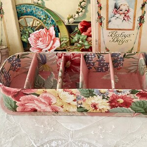 May include: A pink floral patterned box with four compartments. The box is made of cardboard and has a floral design on the outside. The box is empty and ready to be filled with items.