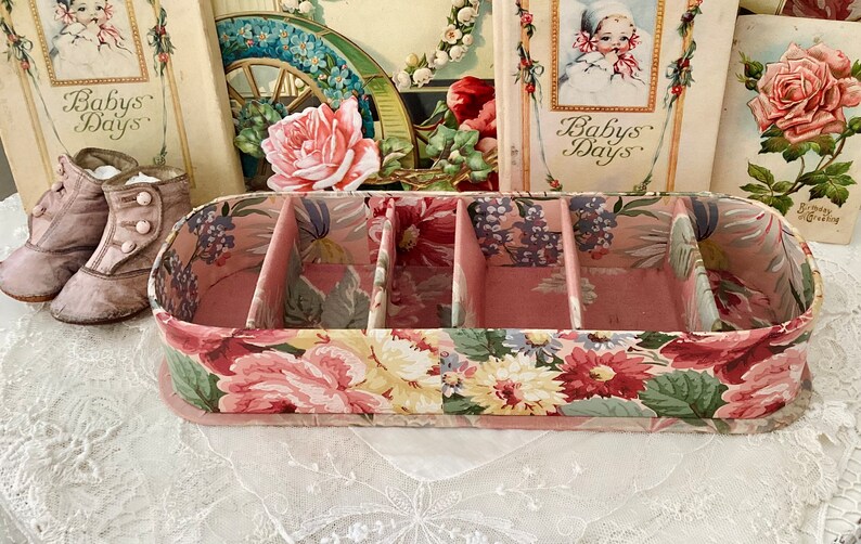 May include: A pink floral patterned box with four compartments. The box is made of cardboard and has a floral design on the outside. The box is empty and ready to be filled with items.