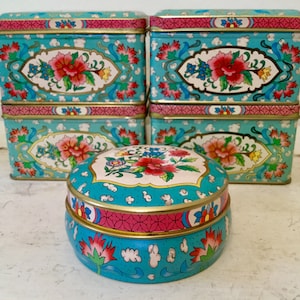Peut inclure: Ensemble de six boîtes en étain vintage de couleur bleu sarcelle et rose à motifs floraux avec une boîte ronde en étain de couleur bleu sarcelle et rose à motifs floraux au centre.