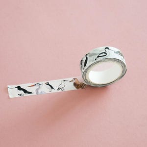 May include: A roll of white adhesive tape featuring a repeating pattern of various bird illustrations, including puffins, herons, and sandpipers in black, white, gray, and brown tones, with a portion of the tape unrolled to display the designs.