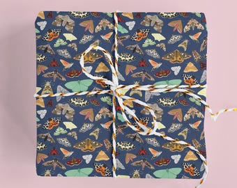 May include: A square gift box wrapped in dark blue paper featuring a repeating pattern of various moth species in shades of orange, yellow, green, brown, and white. The package is tied with a white and orange twisted cord string.