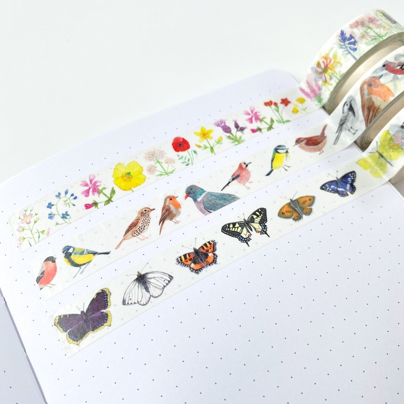 Pode incluir: Rolos de fita washi decorativa com ilustra&ccedil;&otilde;es em aquarela de p&aacute;ssaros, borboletas e flores. Os desenhos da fita incluem v&aacute;rias esp&eacute;cies de p&aacute;ssaros, borboletas coloridas e padr&otilde;es florais.