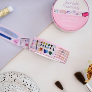 May include: A roll of pink washi tape featuring illustrations of art supplies including paint palettes, colored pencils, and brushes, with the text Sarah Frances and Art Supplies on the packaging and the phrase I am an artist on the tape.