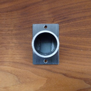 May include: A silver metal curtain rod end cap with a round opening. The end cap is mounted on a wooden surface.