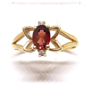 May include: A gold ring with a red gemstone and small diamonds set in a flower design.